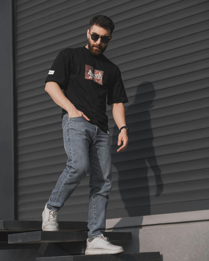 Young man in sunglasses and casual attire poses in urban setting. Perfect for street style and fashion photography.